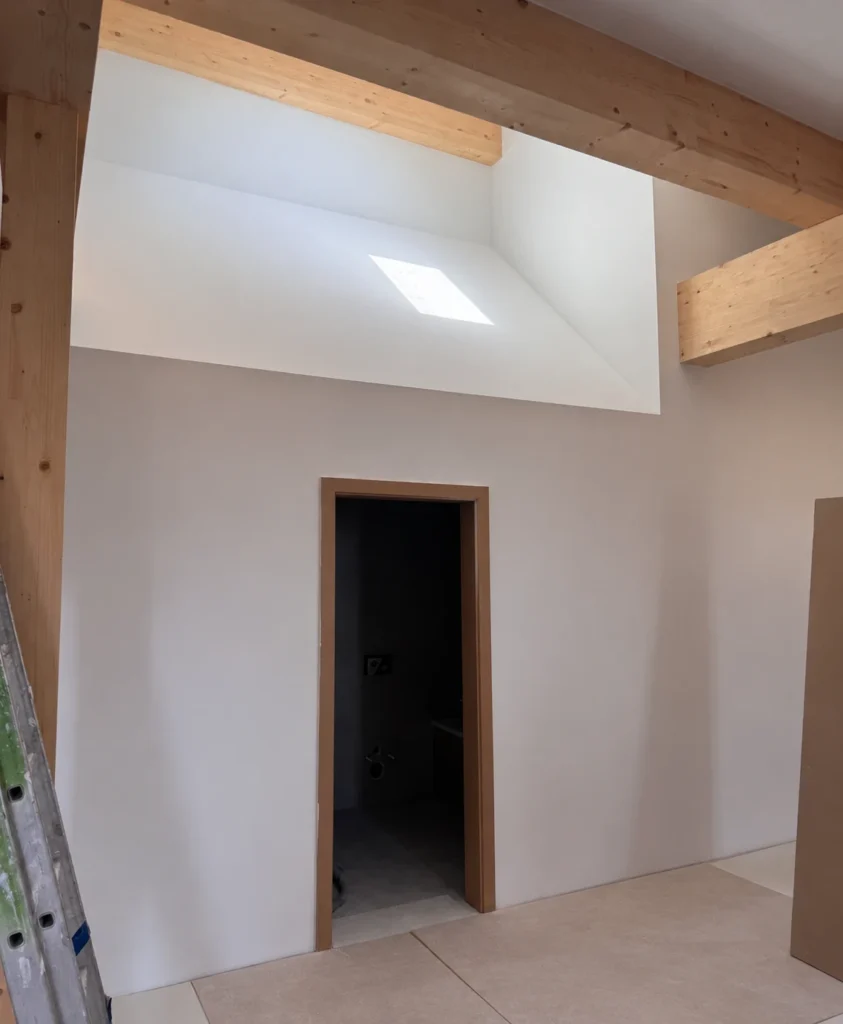 Mur en plâtre et fenêtre de toit sous charpente apparente
